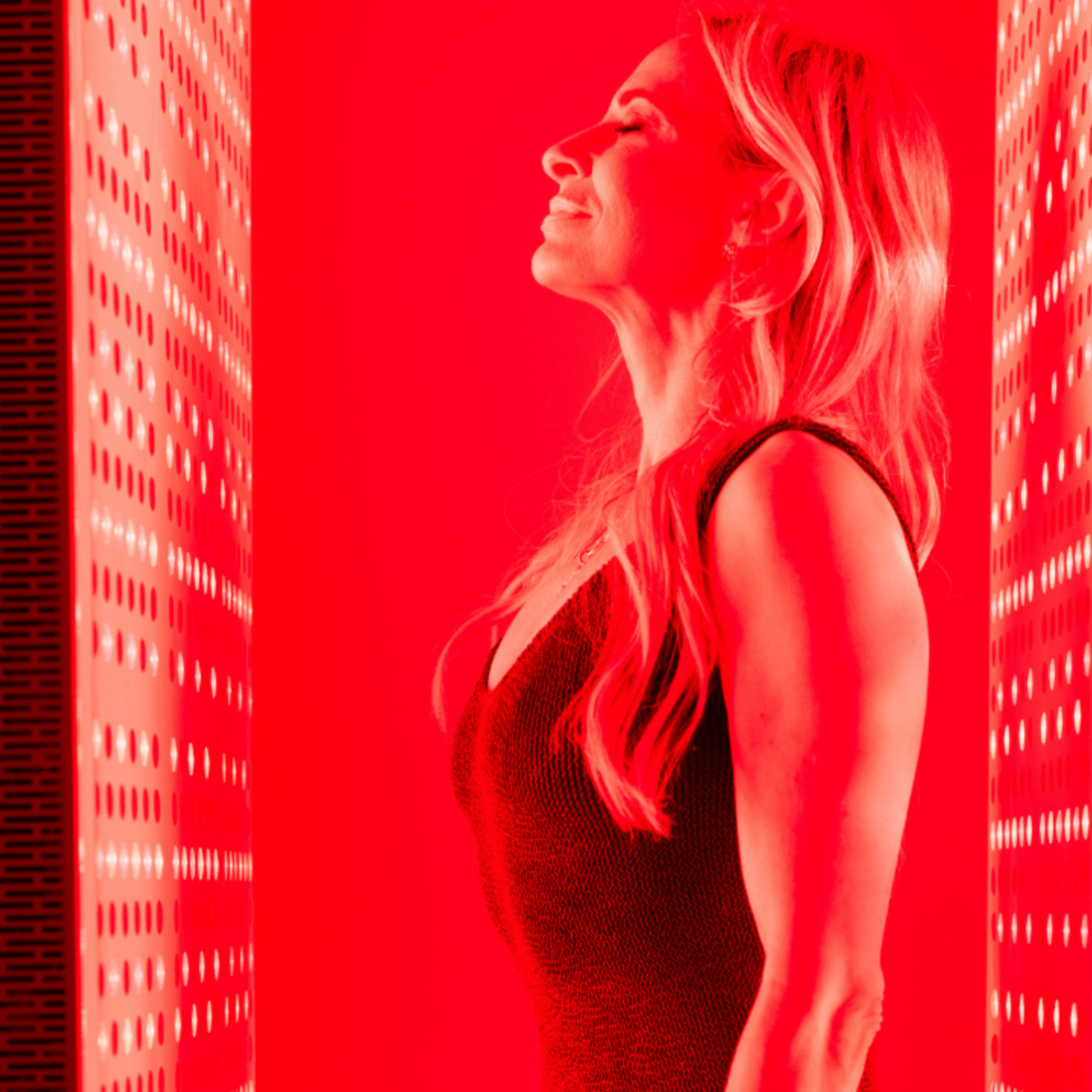 Woman standing between red light therapy panels